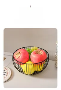 Minimalist black metal wire fruit basket holding grapes and lemons on a light surface