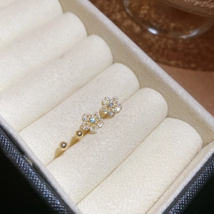 Detailed close-up of golden flower stud earrings with sparkling cubic zirconia in velvet box