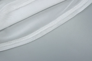 Détail du tissu en mesh blanc montrant des coutures fines et un matériau respirant