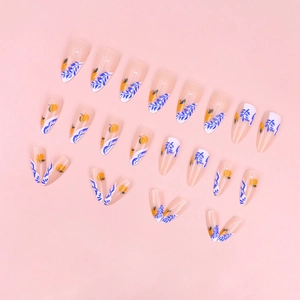 Almond shaped press-on nails with blue leaves and orange fruit patterns on nude base