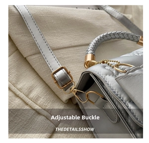 Detail of silver-grey quilted handbag with woven handle and gold adjustable metal buckle