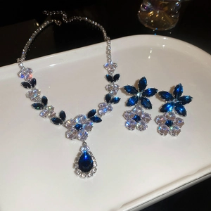Macro shot of silver flower jewelry set with blue and white stones on ceramic tray
