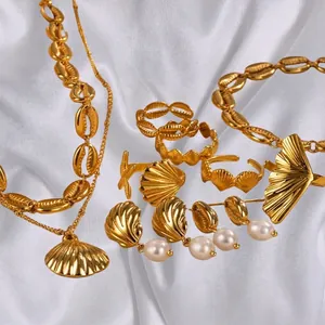 Golden ocean jewelry set with shell charms, ginkgo earrings, and pearls on white silk
