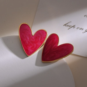 Macro shot of rose red heart earrings with gold trim and marble glaze texture on stone