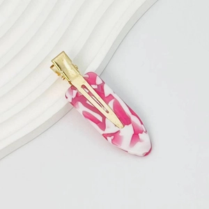 Detailed view of pink marble pattern oval hair clip with gold metal duckbill clip