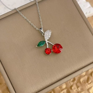 Exquisite cherry pendant necklace with red crystals and silver chain on a beige jewelry box