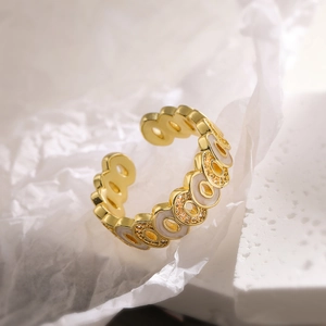 Macro shot of gold-plated hollow geometric ring with white enamel and pavé zircon details