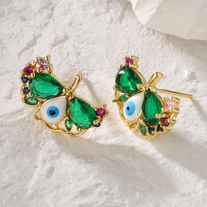 Exquisite gold butterfly stud earrings with emerald zircon and evil eye accents on marble