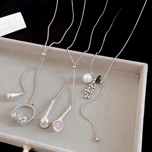 Silver pendant necklaces with tiger eye, pearl, headphones, and tennis racket charms