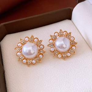Détails macro des boucles d'oreilles vintage en or avec perles blanches et cristaux