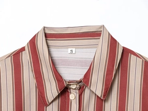 Détail du col et de l'étiquette taille S sur une chemise en coton à rayures verticales