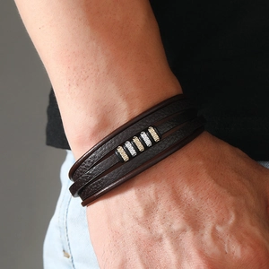 Detail of multi-layer brown leather bracelet with silver and gold beads on wrist