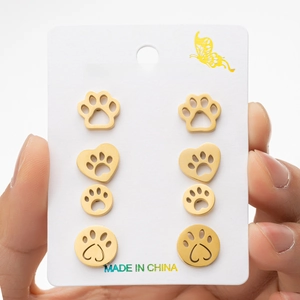 Detailed view of four pairs of golden stainless steel pet paw print stud earrings on a card