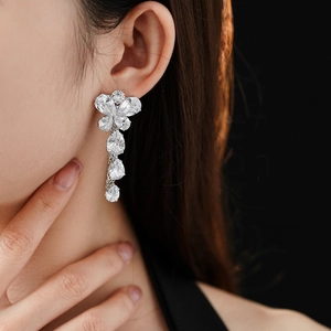 Close-up of elegant flower and teardrop earrings with sparkling zircons on a model