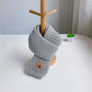 Detail of grey knitted scarf featuring a cute bear leather patch for kids