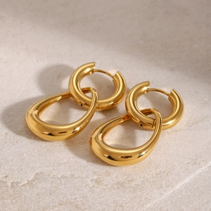 Close-up of gold-plated hoop earrings featuring a thick ring and a teardrop-shaped pendant