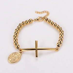 Vue détaillée d'un bracelet doré à perles avec médaille de Saint Benoît et pendentif croix