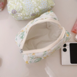 Close-up of floral quilted cotton makeup bag with white zipper and soft texture