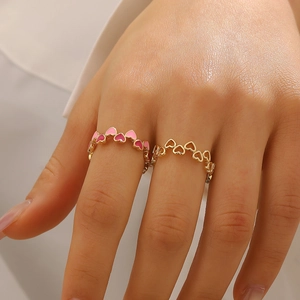 Dettaglio del set con anello cuore in smalto rosa e anello dorato traforato
