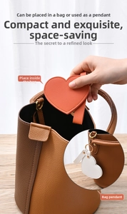 Macro view of heart-shaped leather compact mirror with gold keychain and strap attachment