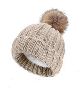 Close-up of beige knit beanie featuring thick plush lining and brown faux fur pompom detail