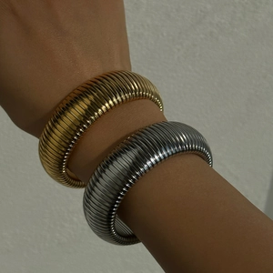 Polished 18k gold and silver tubogas elastic cuff bracelets on a female wrist