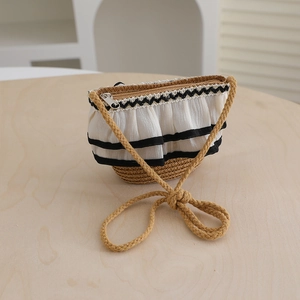 Detail of child's straw bag with lace trim, pleated fabric, and woven rope shoulder strap