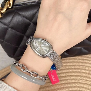 Close-up of silver quartz watch with oval dial and metal mesh strap worn on wrist
