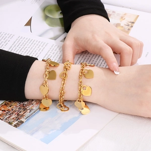 Detailed view of layered 18K gold-plated chunky chain bracelets with polished heart charms