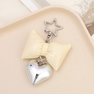 Detail of beige faux leather bow and silver metal heart charm on star hook keychain
