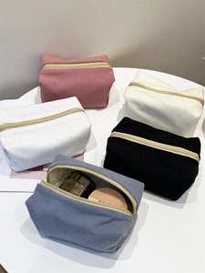 Detail shot of multi-color corduroy makeup bags showing storage capacity on a table