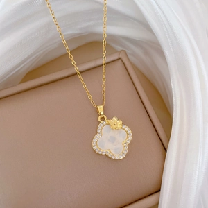 Macro shot of clover pendant necklace with white shell and crystals on silk fabric