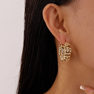 Détail de boucles d'oreilles dorées en U avec strass scintillants et design torsadé