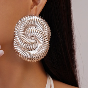 Détail macro de boucles d'oreilles spirales argentées avec texture rayonnante en métal