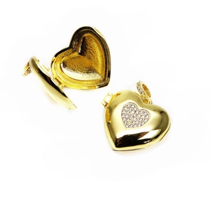 Detail of open and closed gold-plated heart locket pendants with shimmering crystal accents