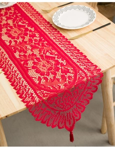 Macro detail of red lace table runner with hollow floral mesh and decorative tassels