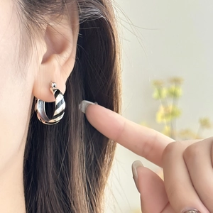 Close-up of zebra pattern hoop earring with black enamel on a model's ear