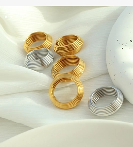 Detailed view of multilayer spiral gold and silver rings on a minimalist ceramic base