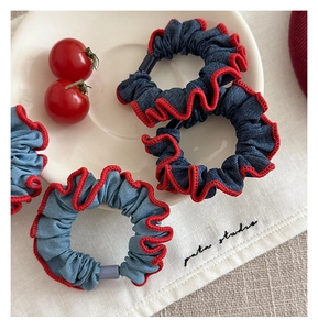 Detailed macro view of denim scrunchies with pleated red contrast edge and secure plastic clasp
