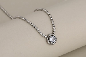 Macro shot of silver-tone chain necklace with round brilliant cut center stone and pavé halo