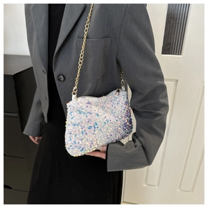 Detail of white sequin crossbody bag with gold chain strap on grey blazer