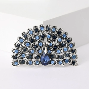 Macro shot of a peacock brooch with blue crystal gradients on a polished silver alloy base