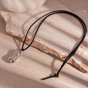 Macro shot of silver peanut pendant with textured surface on stone background