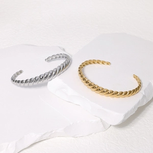 Minimalist twisted titanium steel open cuff bracelet in gold and silver finish on stone