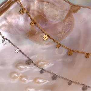 Close-up of gold and silver flower pendants on a shimmering iridescent pearl shell background