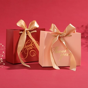 Detail of red and pink gift bags with gold ribbon handles and Thank You foil stamping
