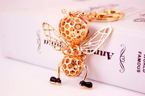 Close-up of golden honey bee keychain with intricate hollow design and black leg details