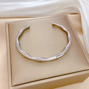 Close-up of silver bamboo joint textured steel bracelet on white silk in a jewelry box