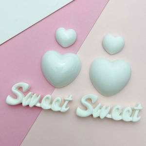 Close-up of heart-shaped resin charms and Sweet letters for DIY jewelry and phone cases