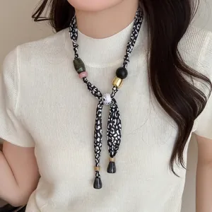 Detail of fabric print necklace with leopard silk ribbon and mixed material beads